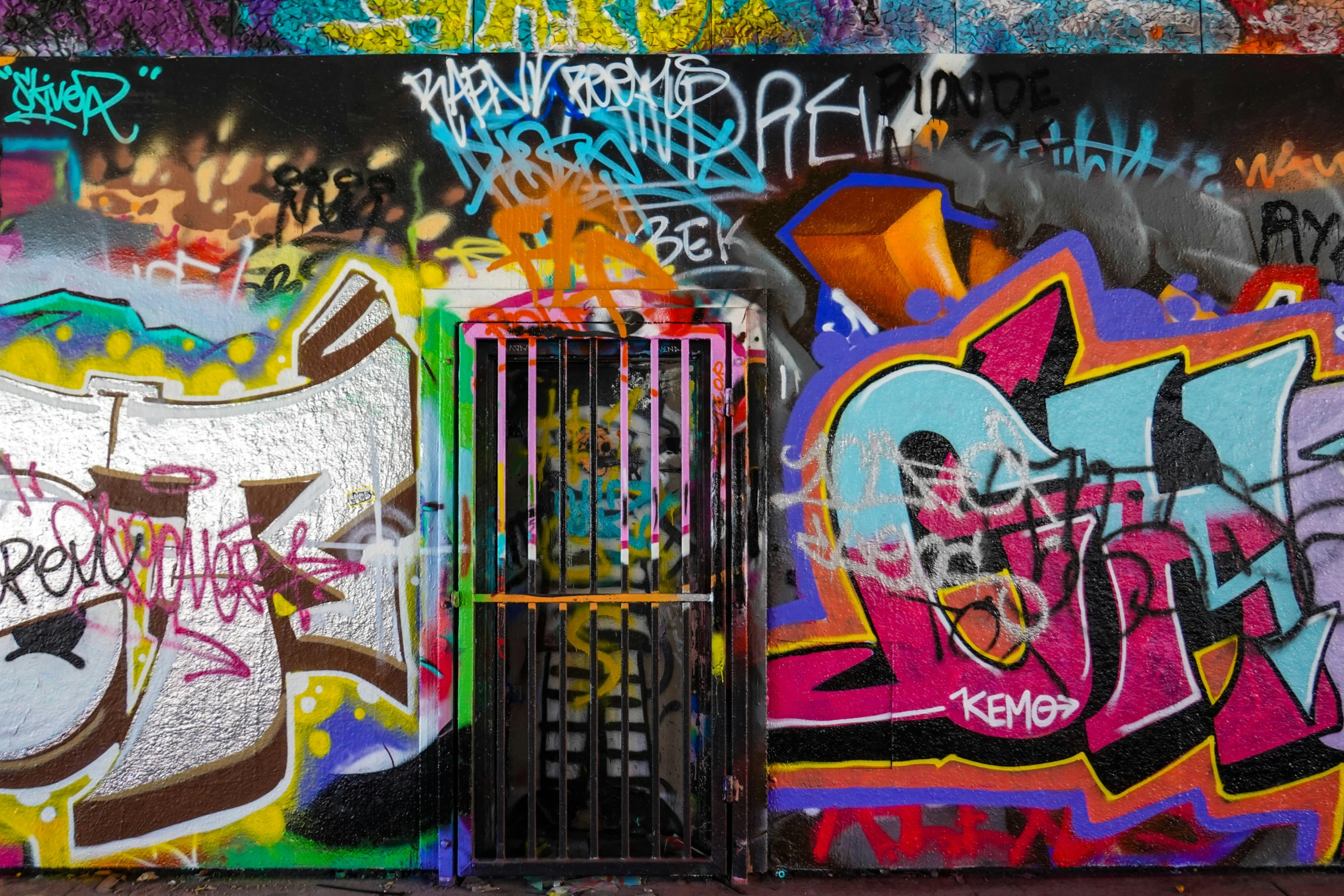 colorful graffiti covers a black metal fence and wall