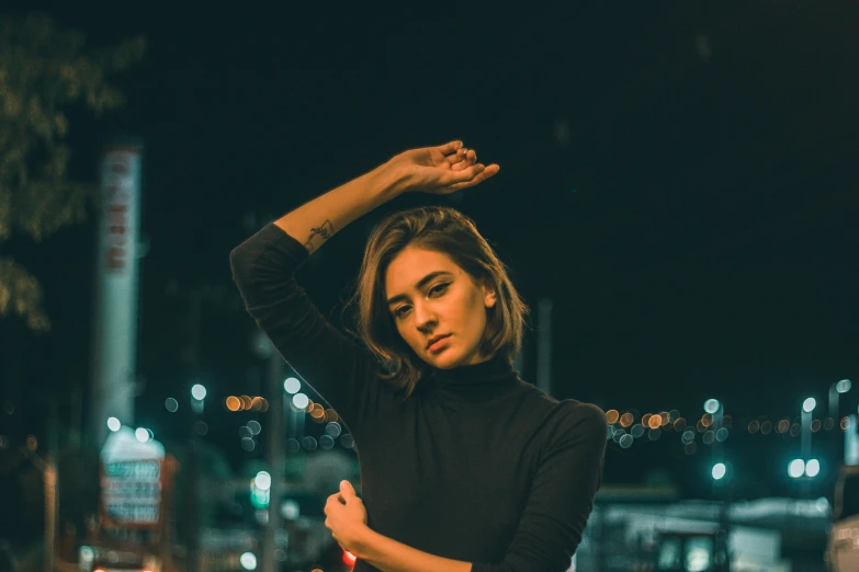 a beautiful woman standing next to a wall on the side of the road