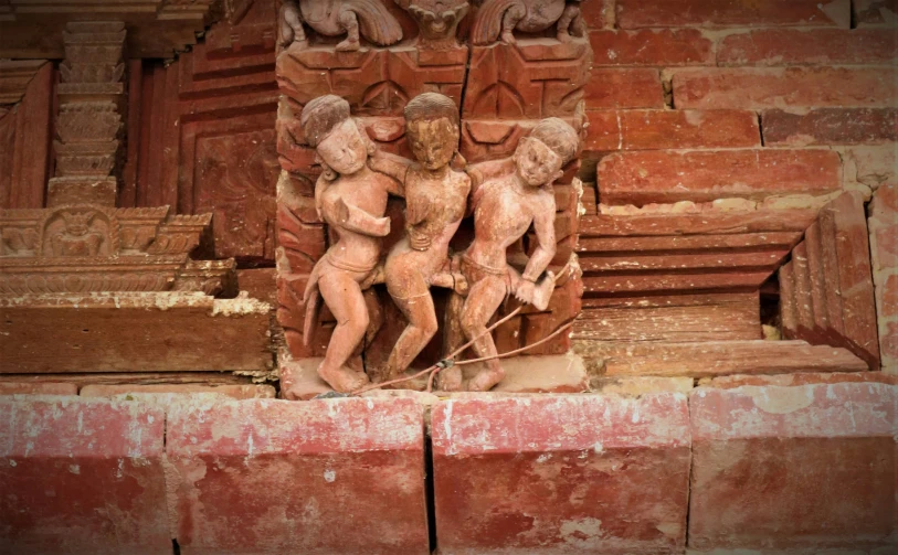 a red stone wall has statues of two angels on it