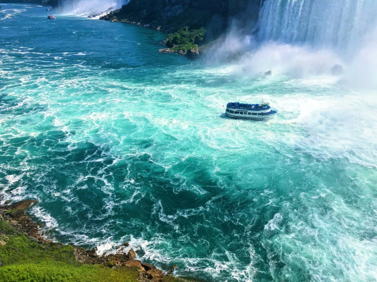 a boat sailing on the water with a waterfall in the background