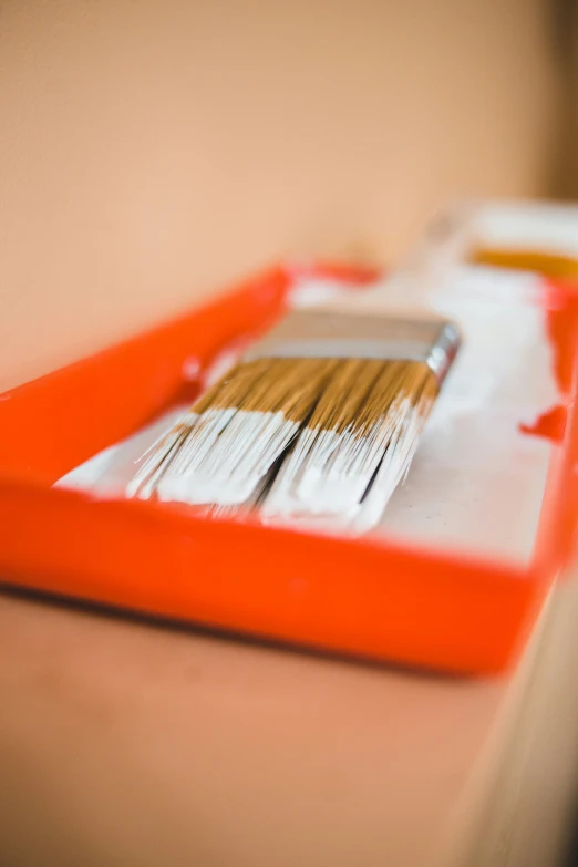 a brush and knife sitting on an orange tray