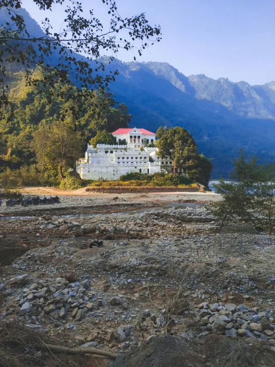 a house is shown along the water side in front of some trees