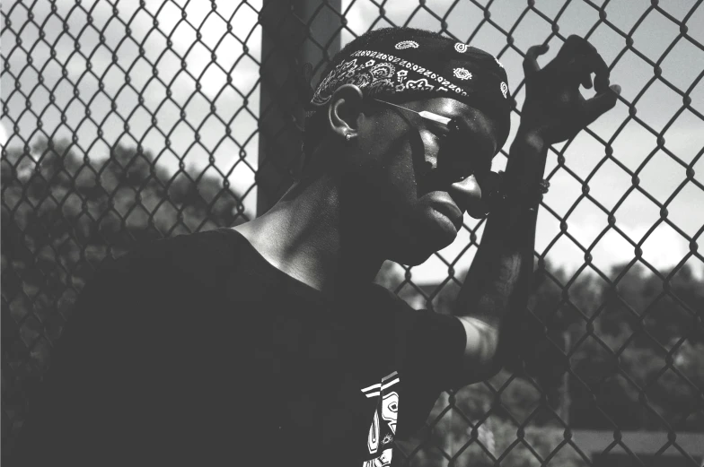 a man wearing glasses is standing near a chain link fence