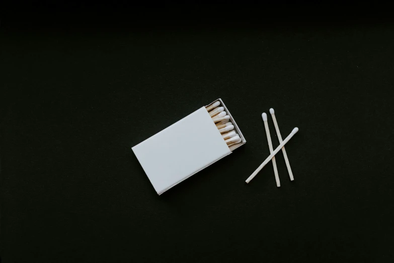 a pack of matches and some match stick on a black table