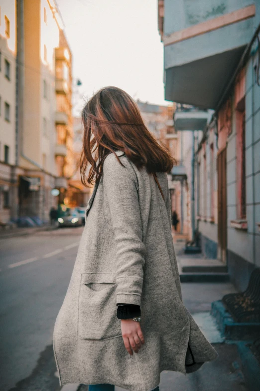 a woman walking down a city street holding her hand behind her back