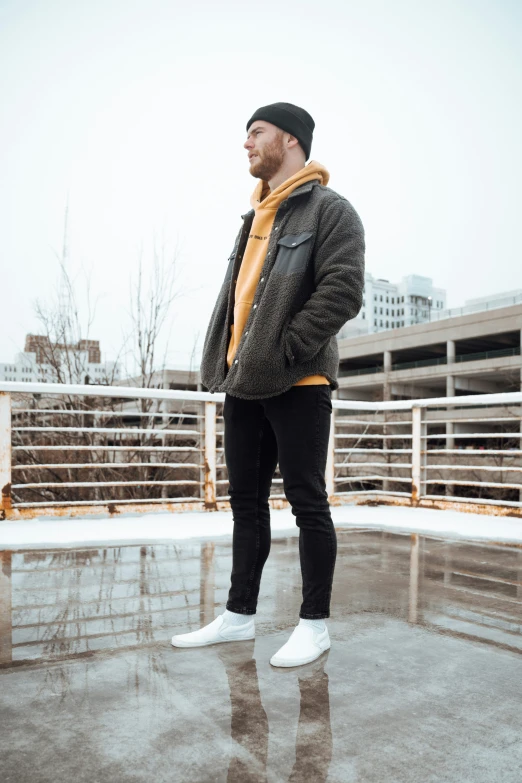 a man in a yellow shirt and black jacket and a pair of white sneakers