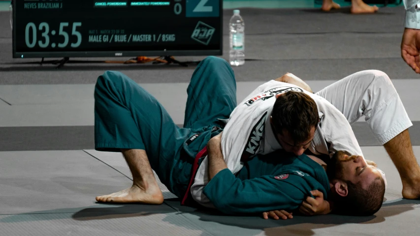 a man lays on the ground next to another man in a green suit