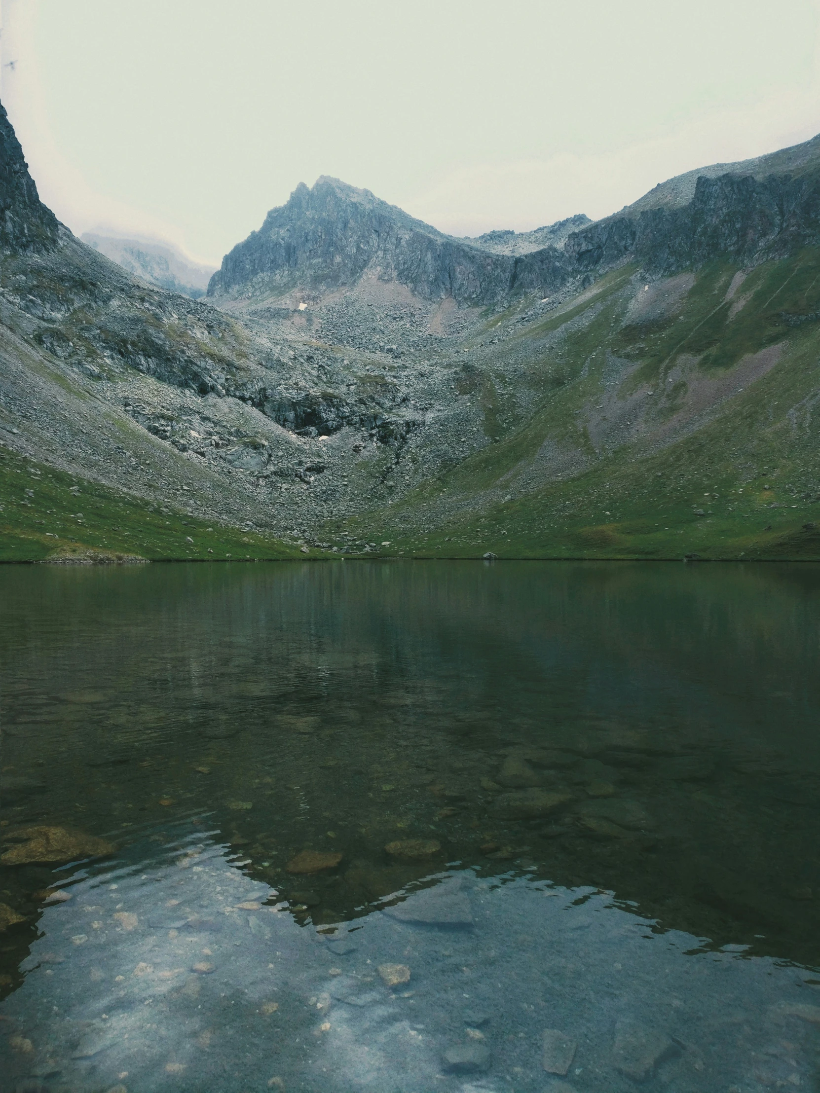 a mountain range is seen reflected in the still water