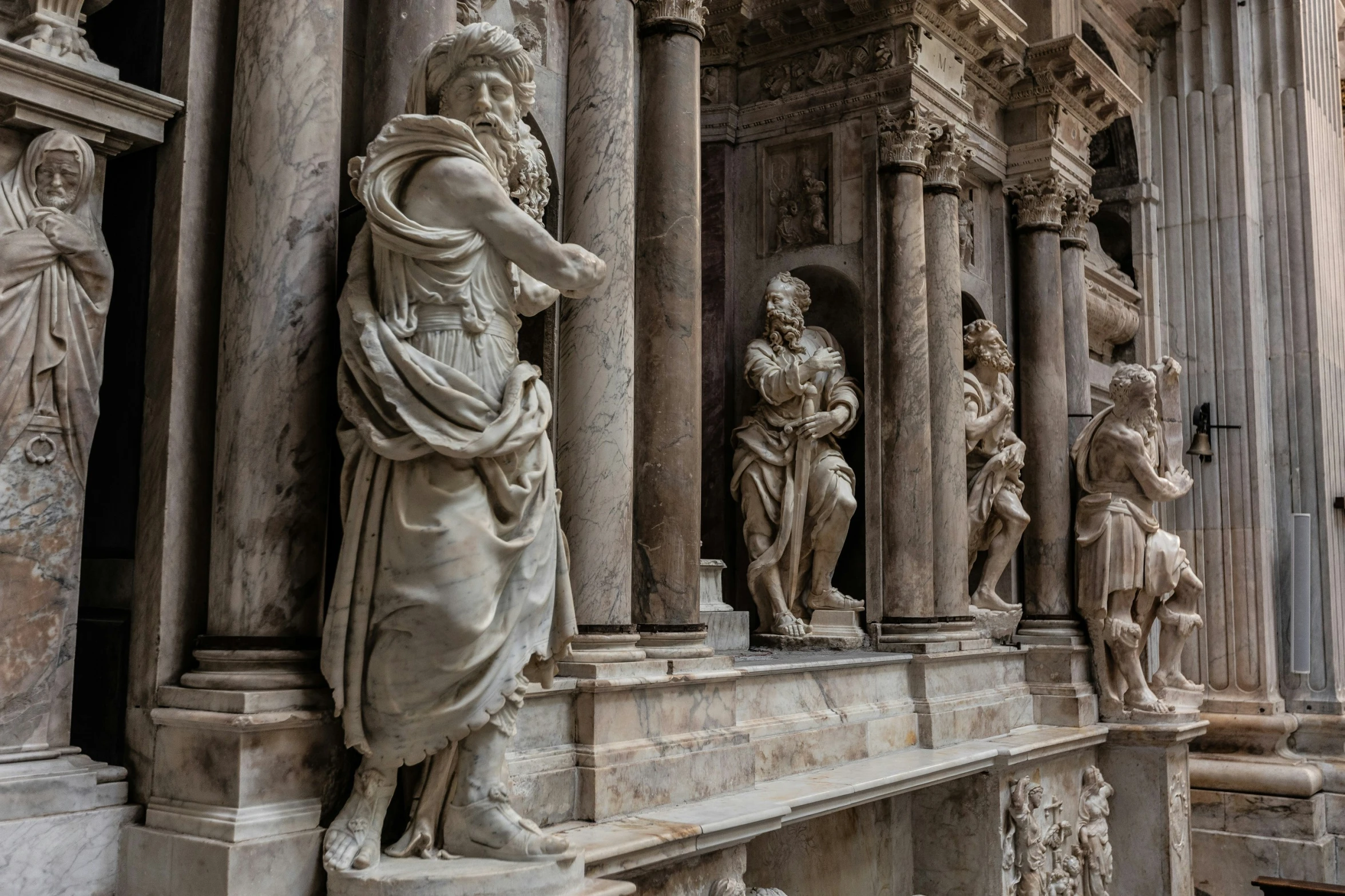 marble statues surround the stone columns of a building