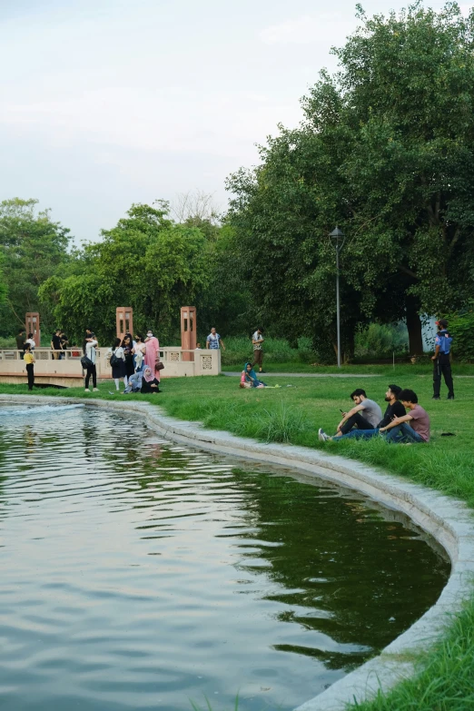 people relaxing in the park by a pond