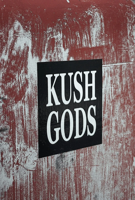 a sticker that says kush gods on a weathered red box