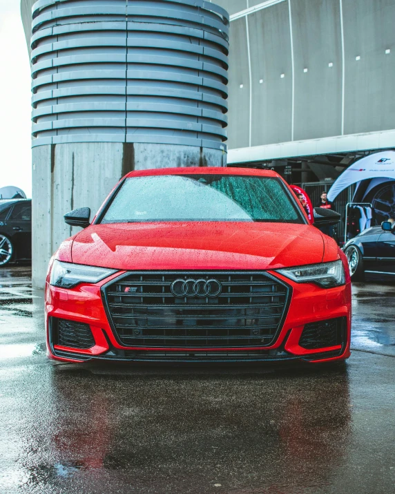 a red car is driving through the rain