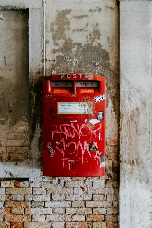 the red trash can with graffiti on it is in a room that is made of old bricks