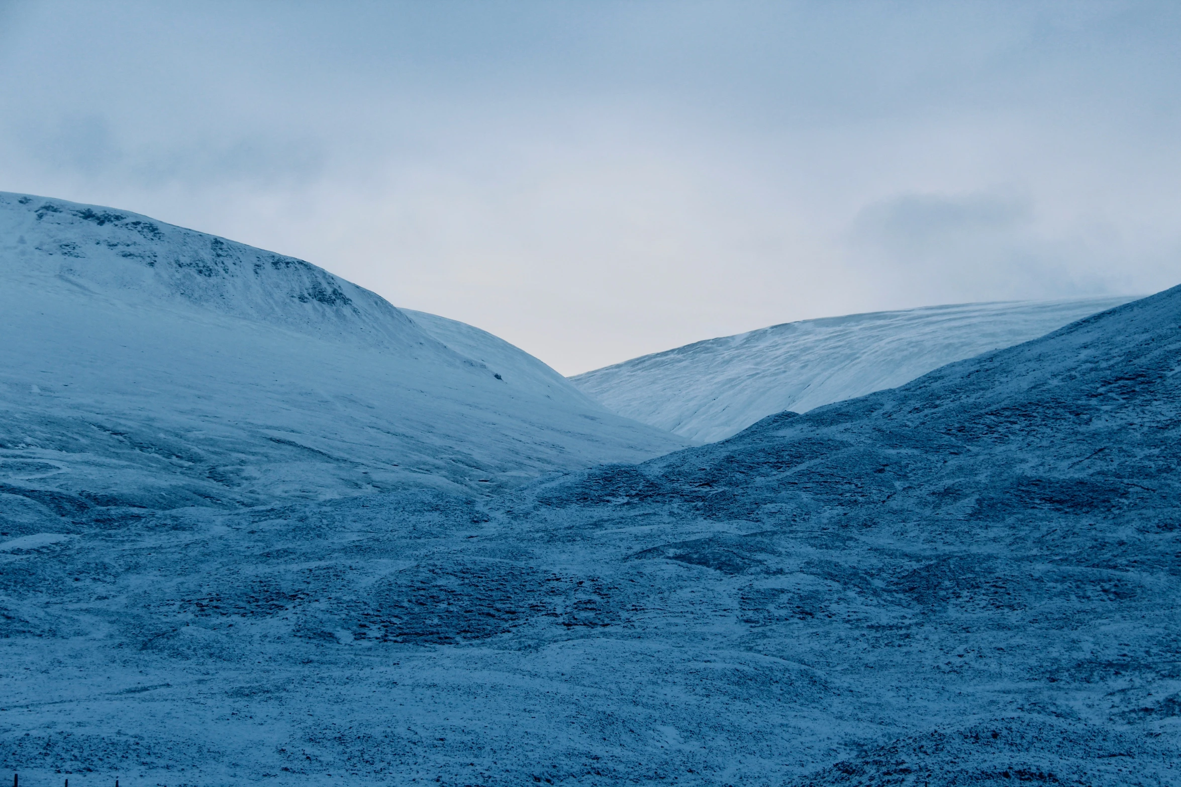 a large snow covered hill with hills in the background