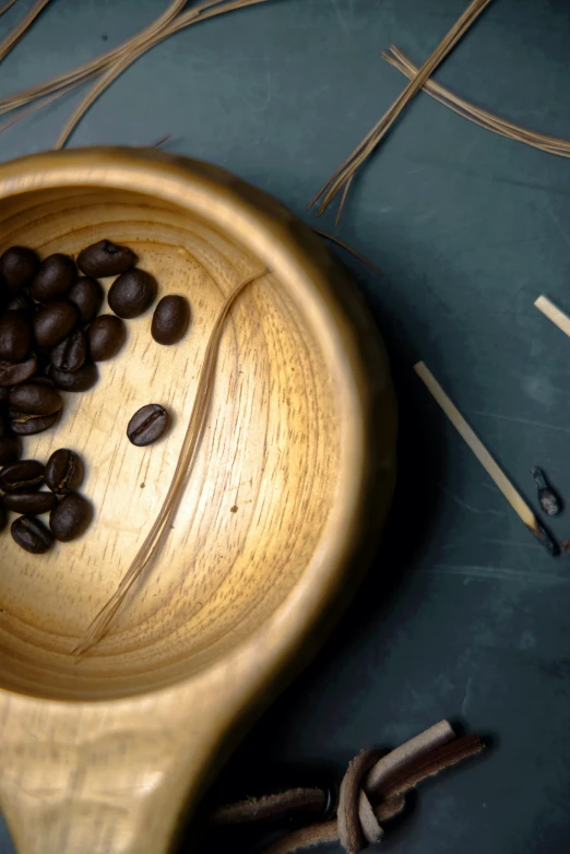 a wooden bowl containing coffee beans and two wooden spoons