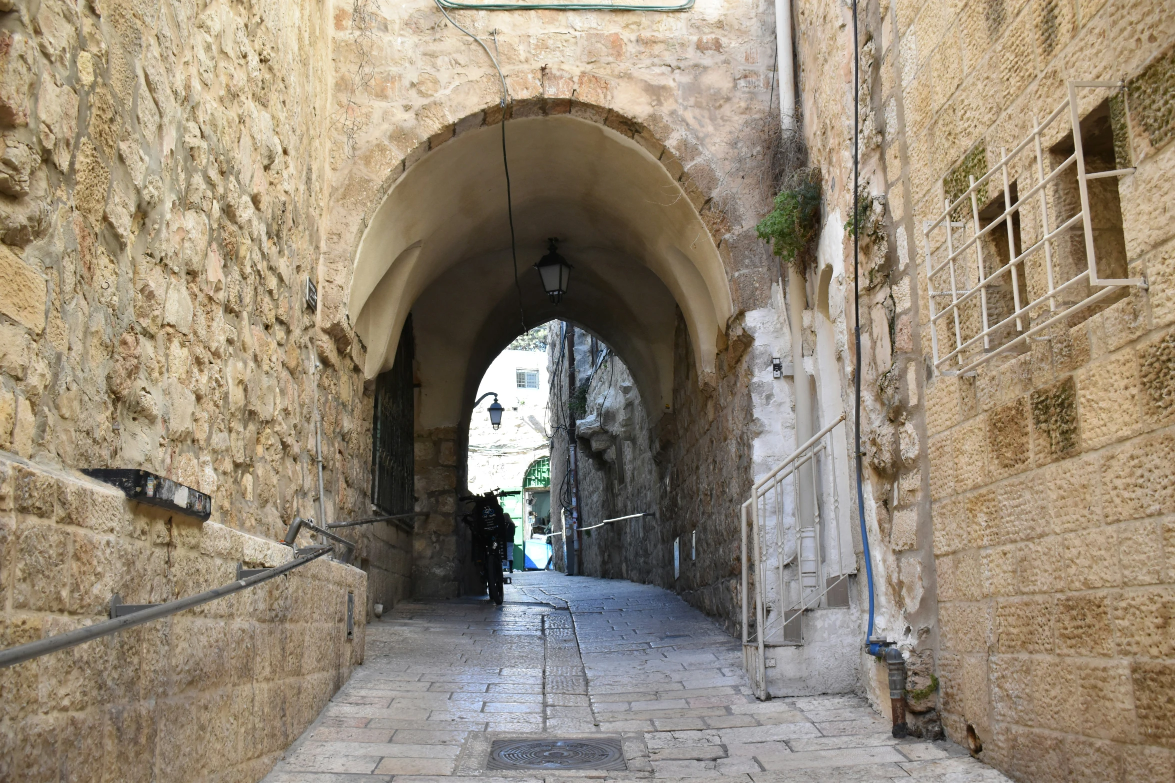 a narrow stone street is lined with archways
