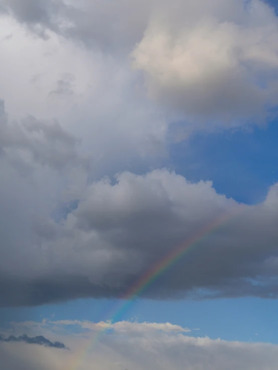 a rainbow shines over the clouds on the horizon