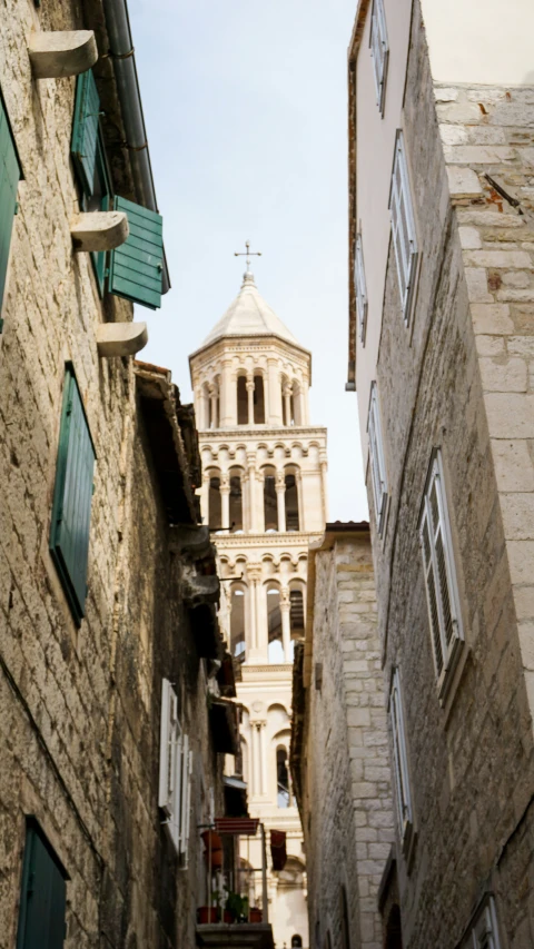 a narrow street with old stone buildings and a tower