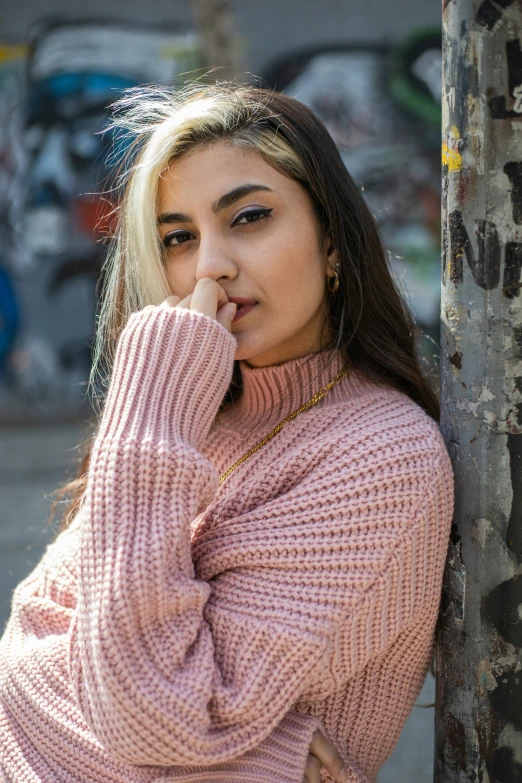 a woman leaning against a tree in a sweater