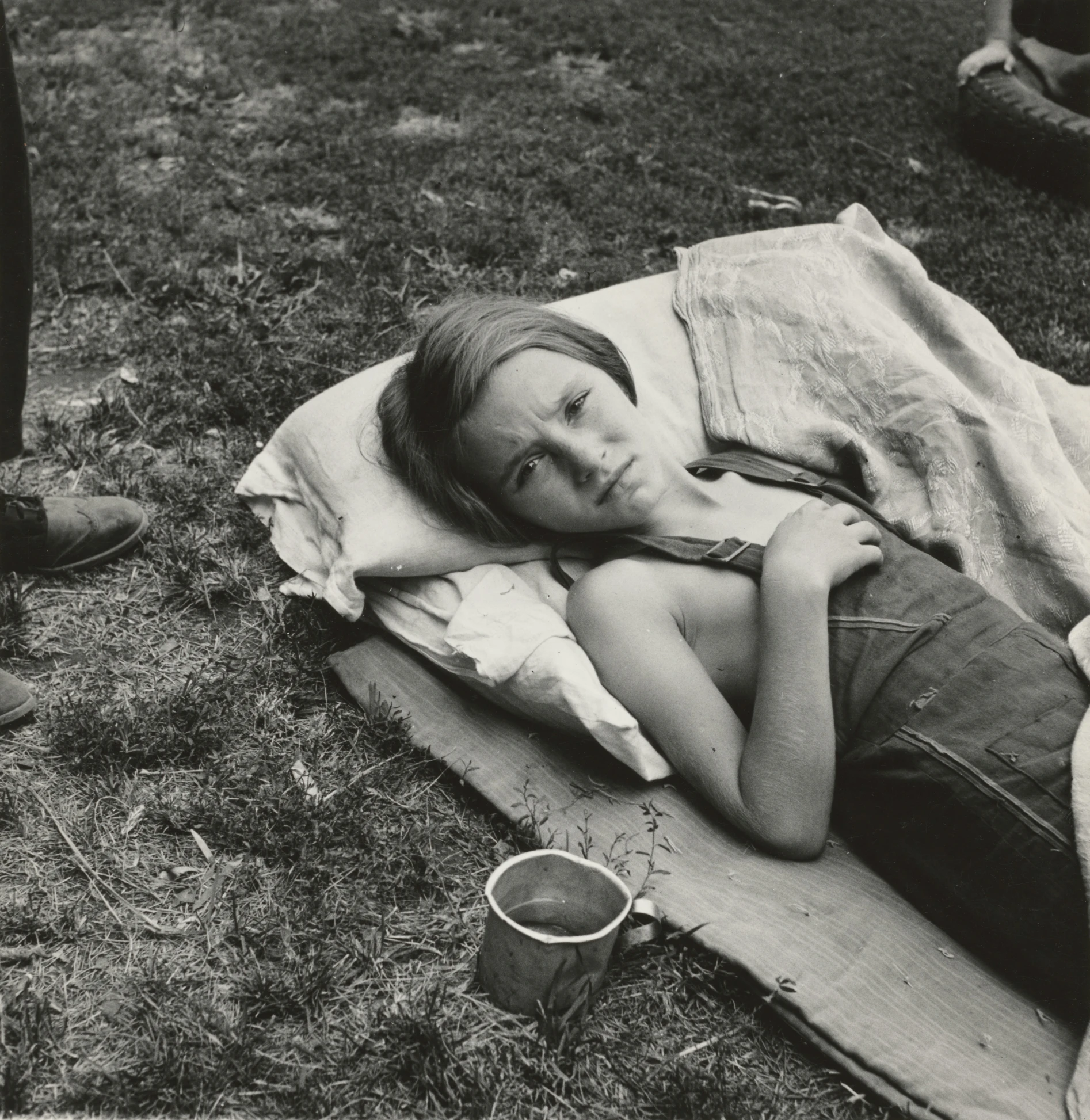 a woman sleeping on a blanket near other people