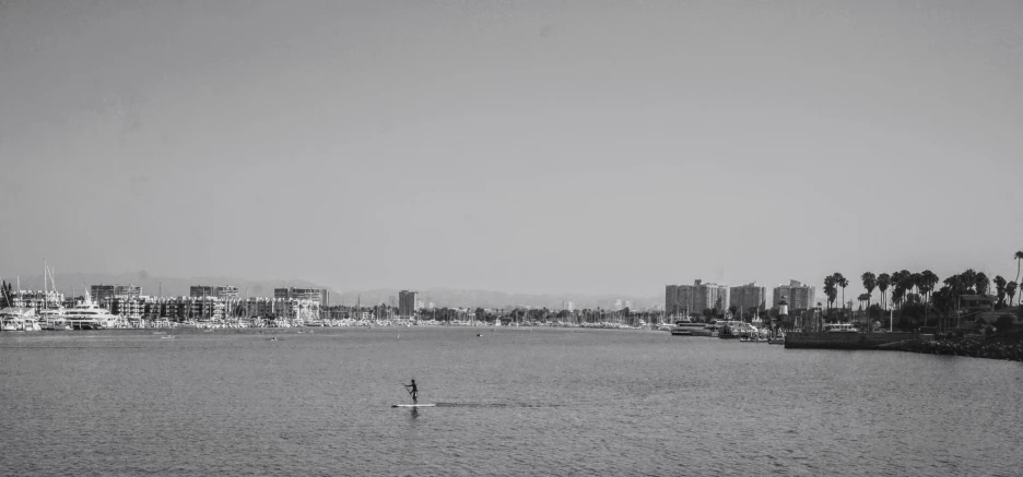 a lone boat out on the water in front of the large city