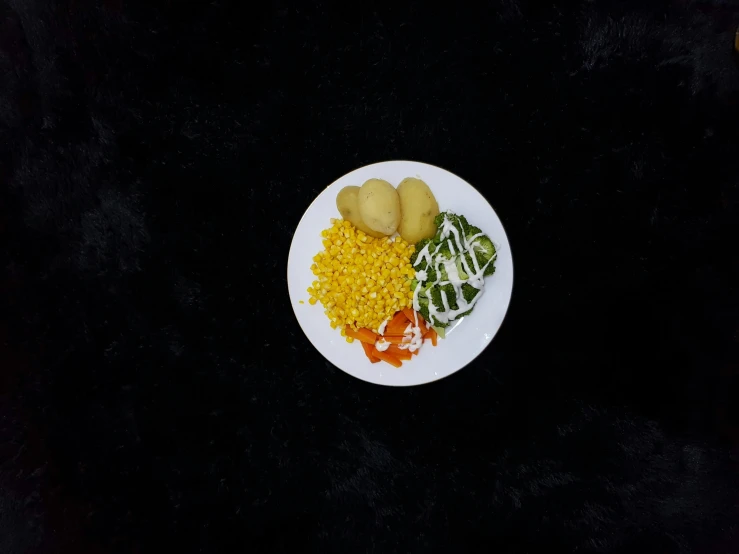 a white plate topped with lots of food on a black surface