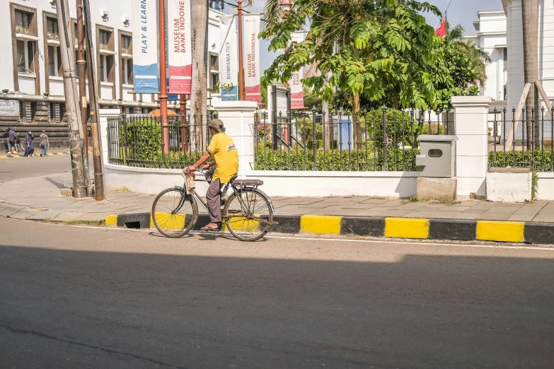 a man on a bicycle is standing at the side of the street