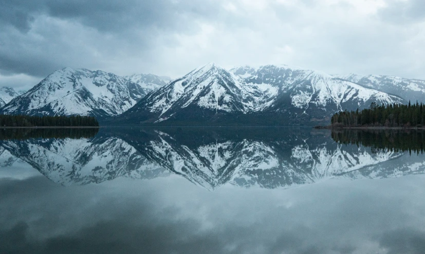 mountains and trees are reflected in the water