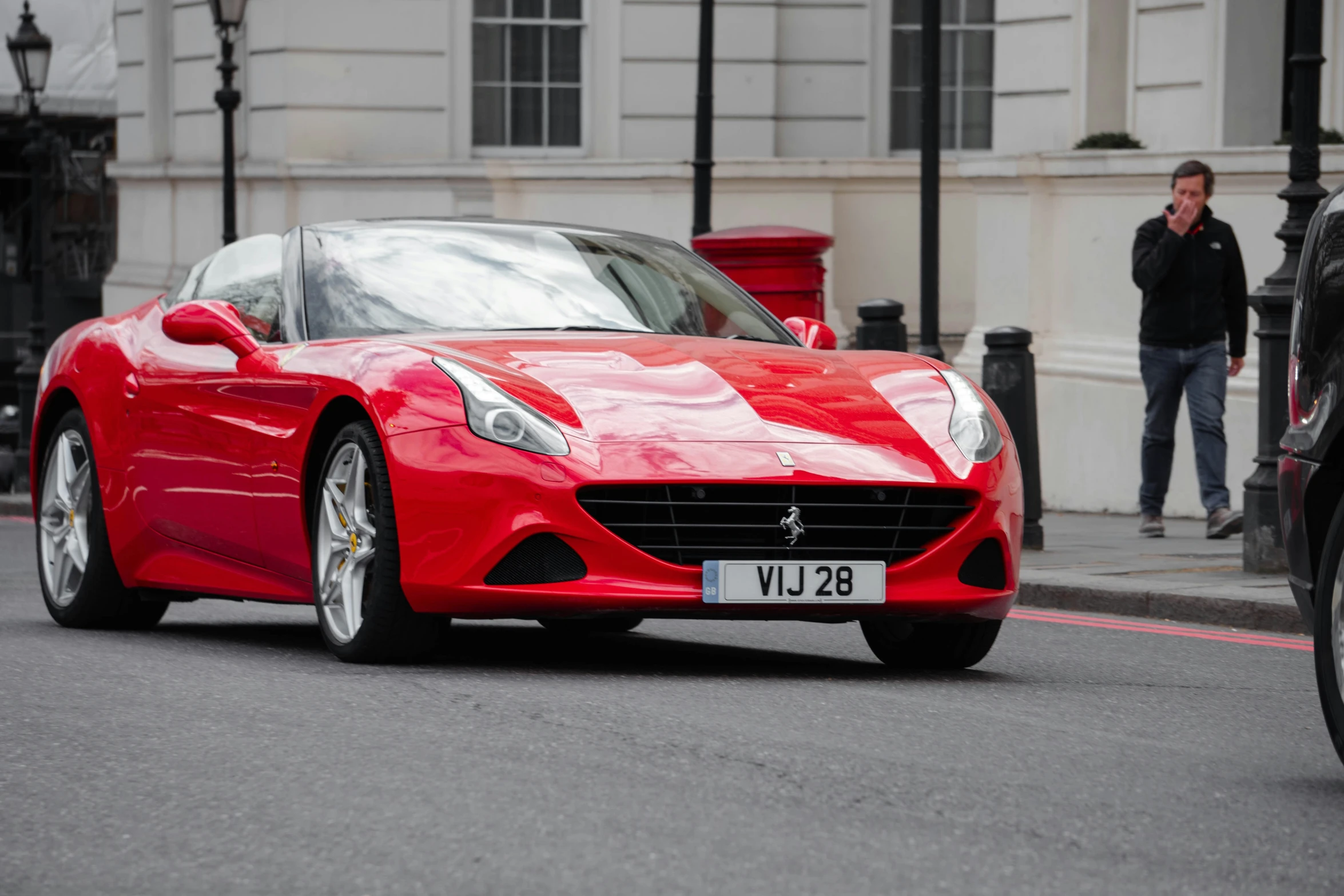 red sport car with silver wheels driving through the city