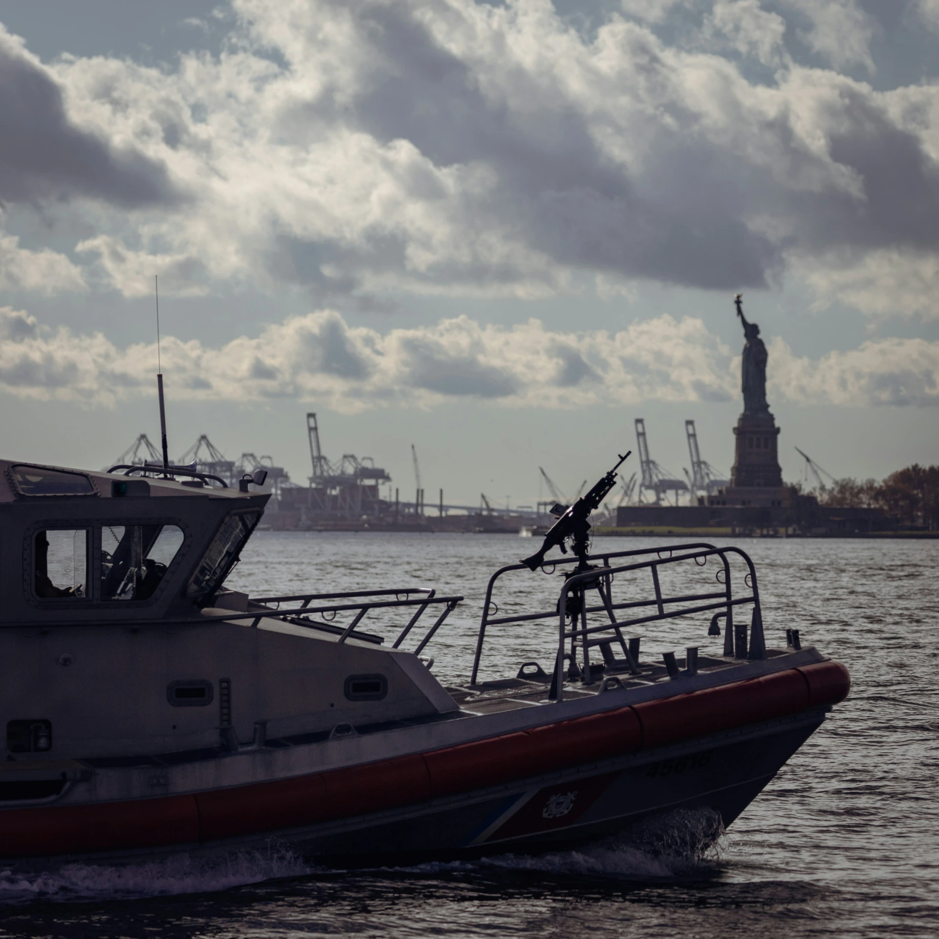 an ocean guard boat out in the ocean next to the statue of liberty