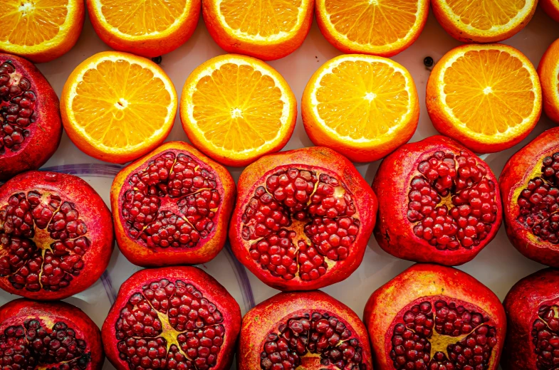 a bunch of sliced oranges and pomegranates sitting on top of a table