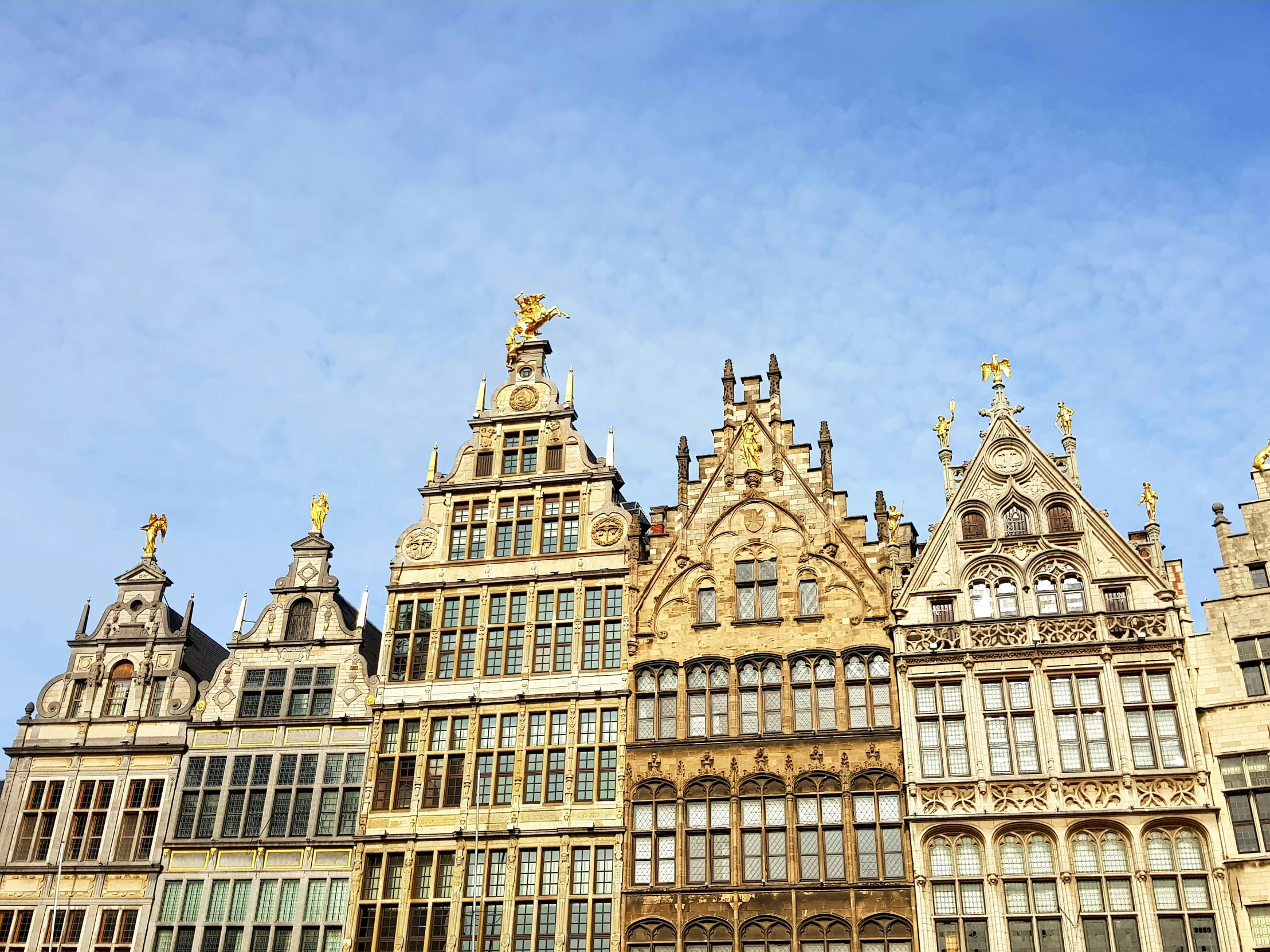 a tall ornate building with two gold statues at the top