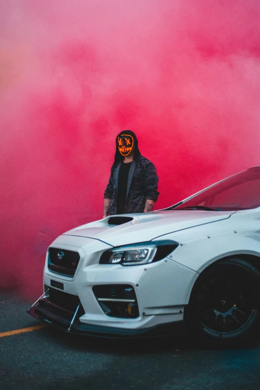 a man stands next to his car with a painted pumpkin face