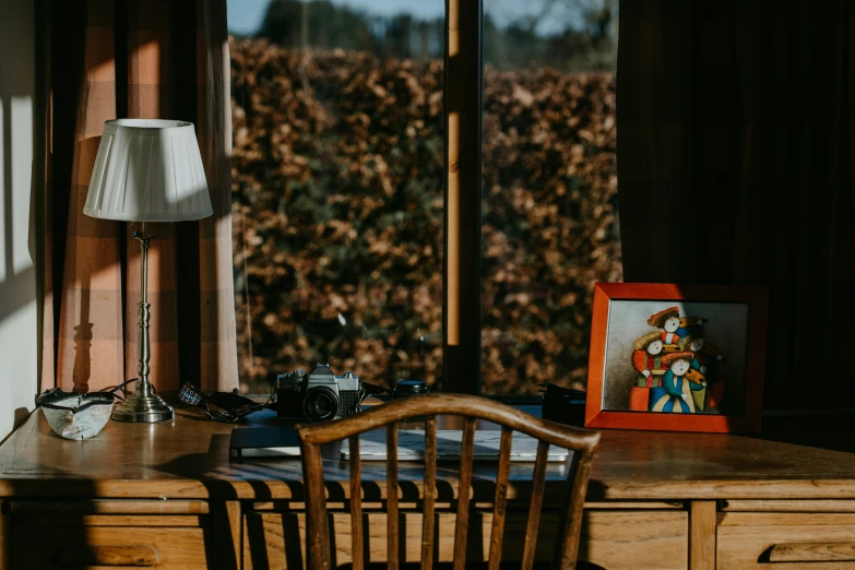 a desk with a lamp, two pictures and a chair