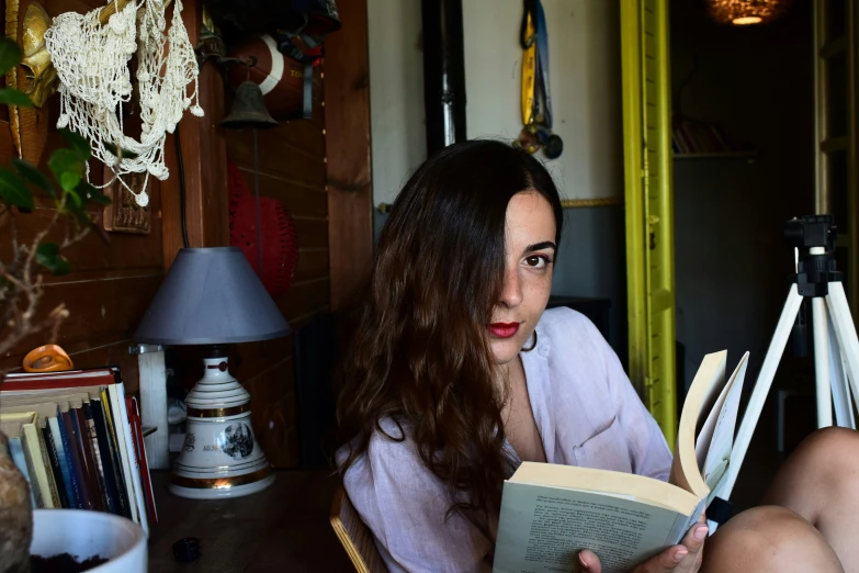 woman reading in chair at table by lamp