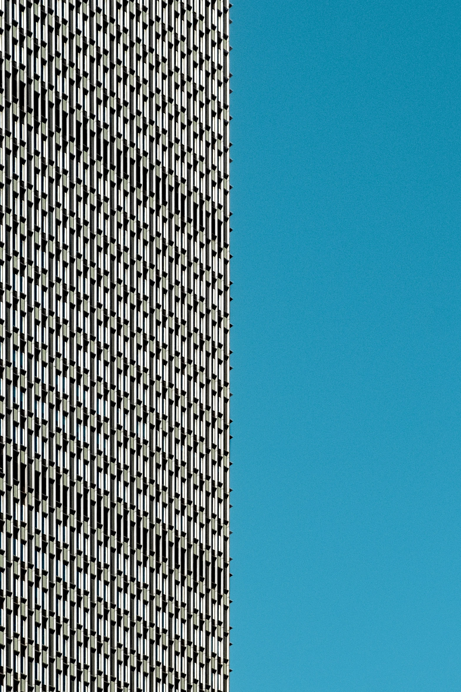 an airplane flying through the blue sky next to tall buildings