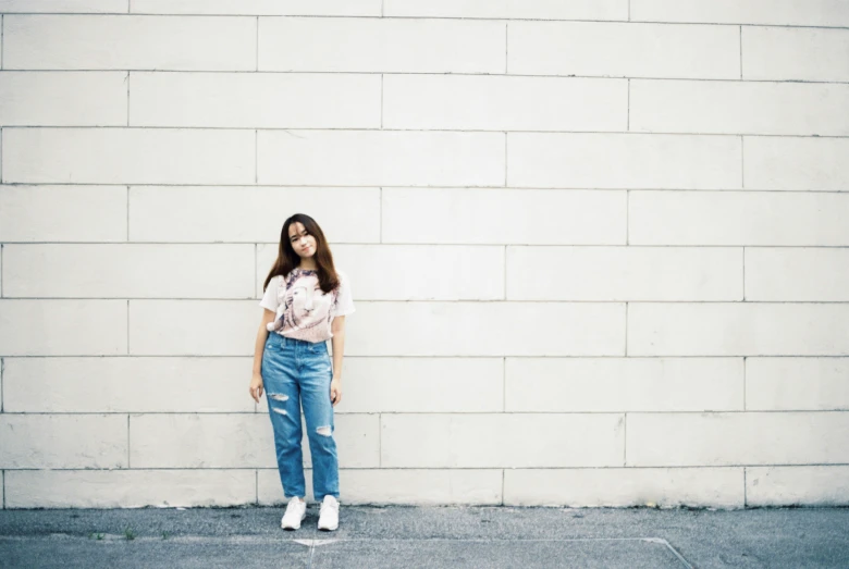 a girl standing in front of a white wall