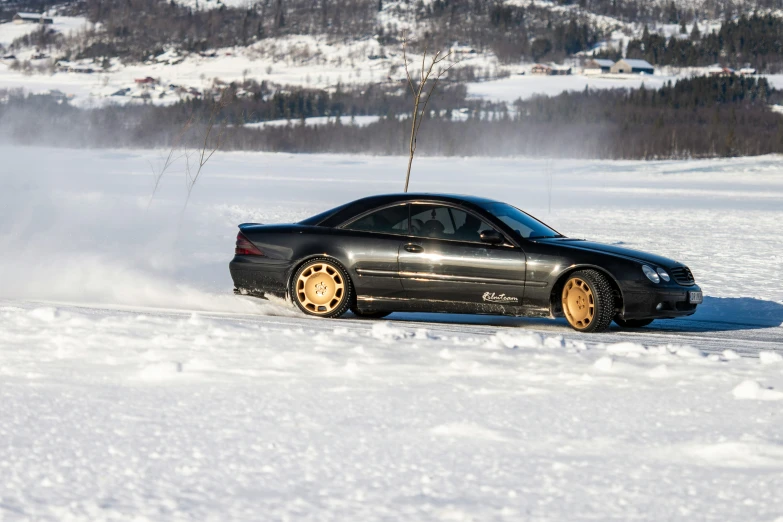 a car kicking up snow in the middle of the road