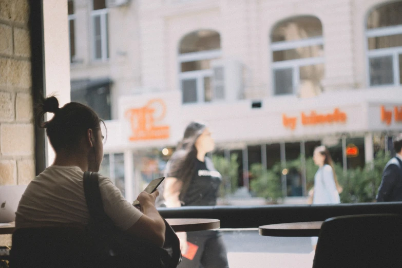 a woman looking at her cell phone on a porch outside a restaurant