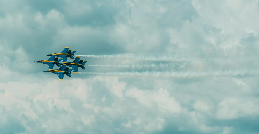 four jets fly through the sky while trailing smoke