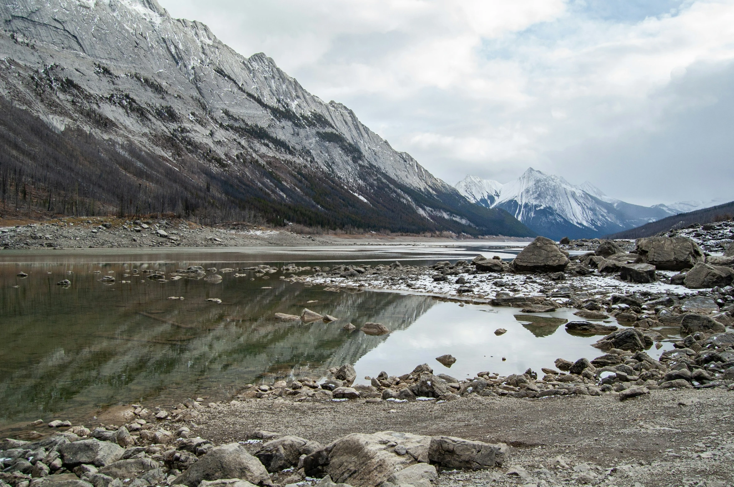 mountains reflected in calm water on a cloudy day