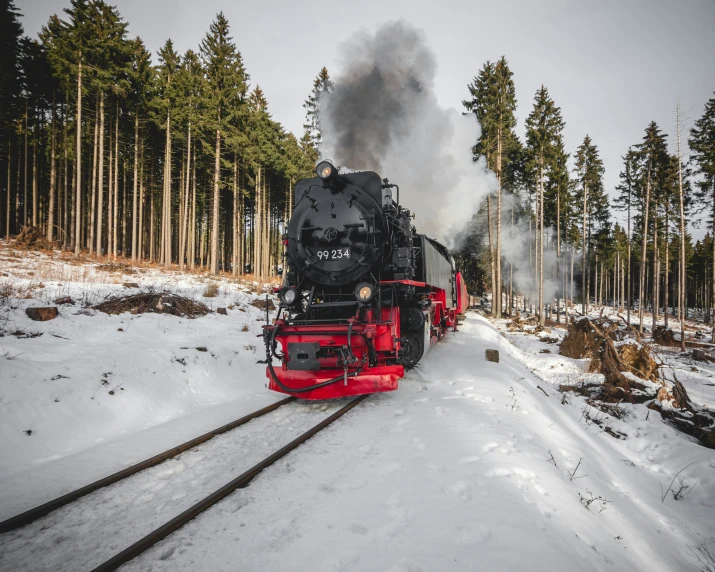 an old train drives down some tracks in the snow