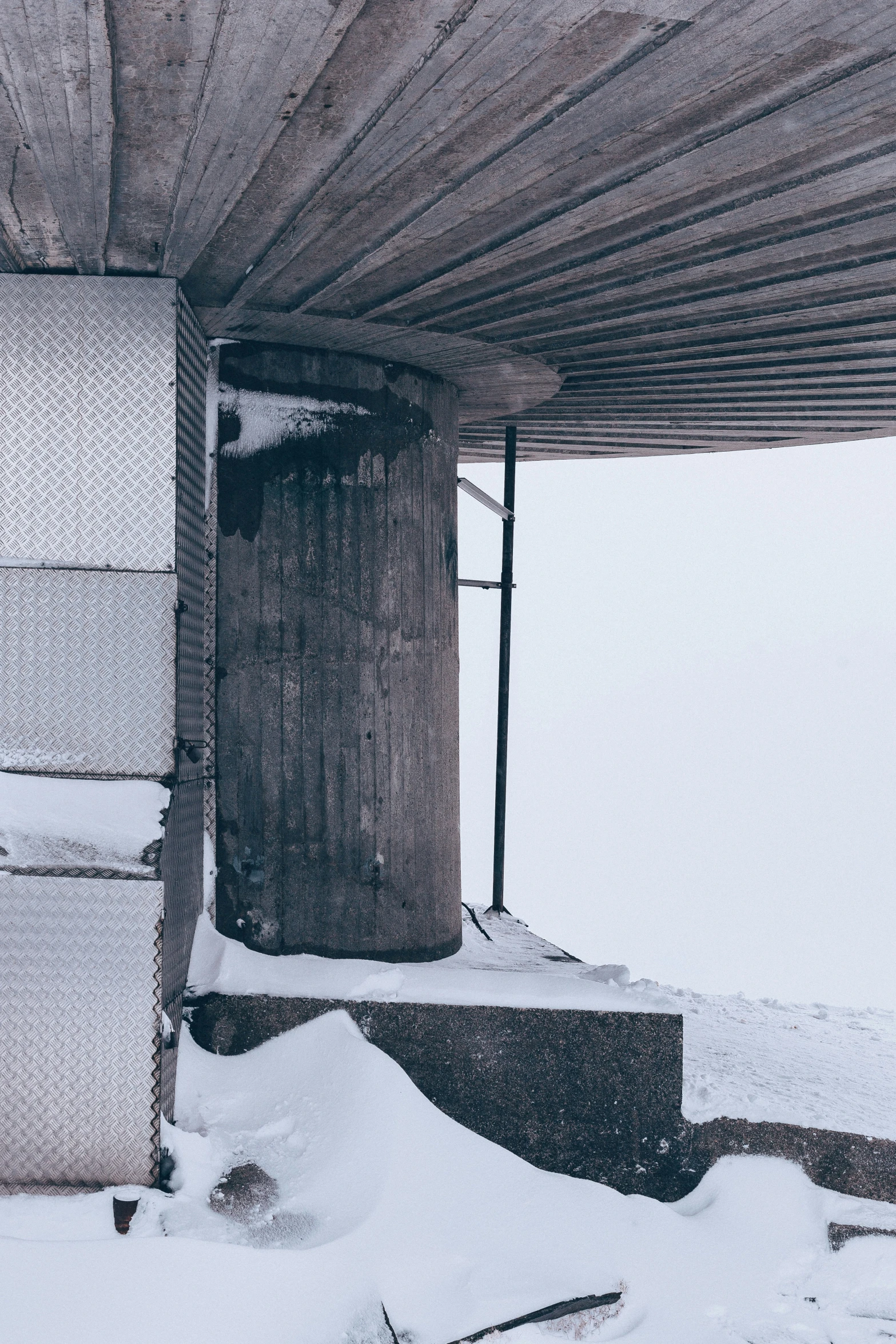 snow covers the ground and a structure that has stairs in front of it