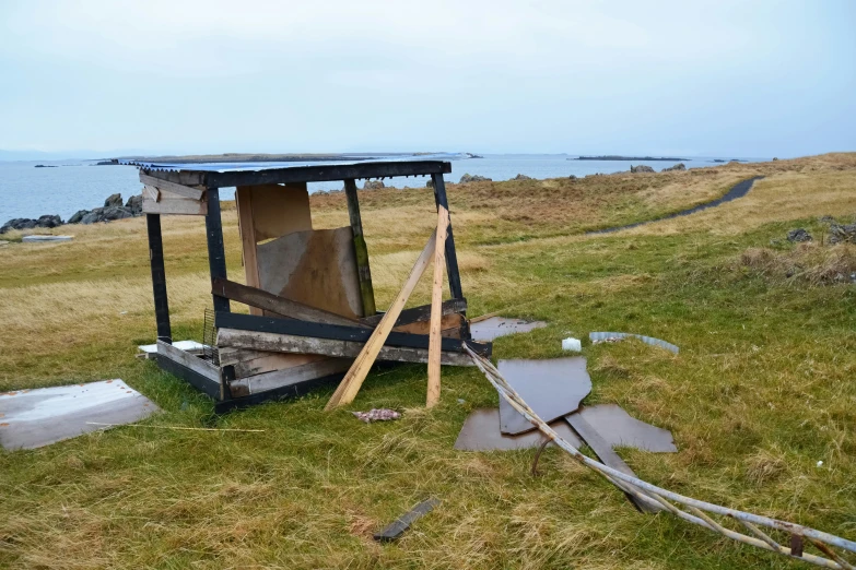 a broken outhouse on top of a hill