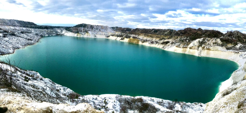 a large green crater lake sits in the middle of the mountains