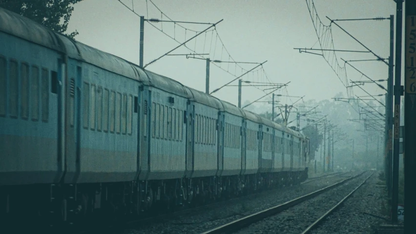 a train traveling past a train station covered in fog