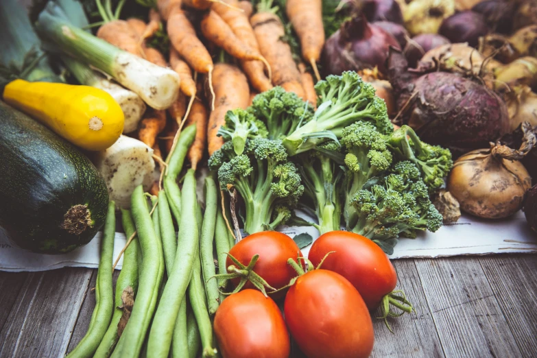 a table with various fresh vegetables and a yellow cucumber