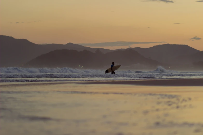 a man standing on a beach holding a surfboard