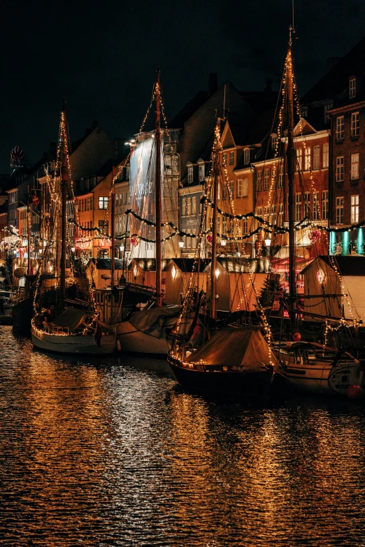 a lighted harbor with boats and buildings in the background