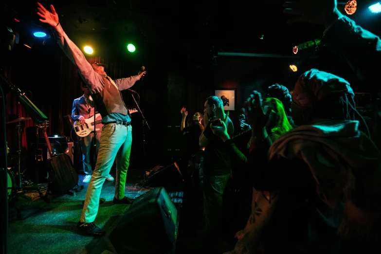 a man playing a guitar on stage while people are clapping